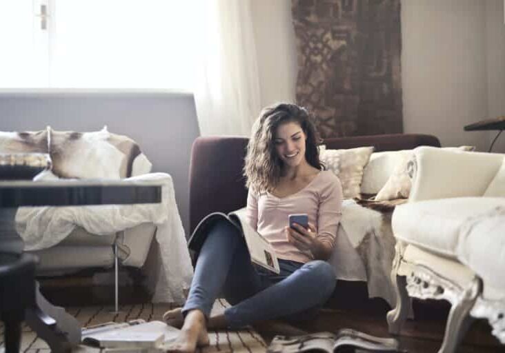 woman reading magazine while on her smart phone woman reading magazine while on her smart phone