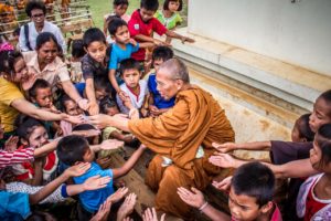monk giving to hungrey children