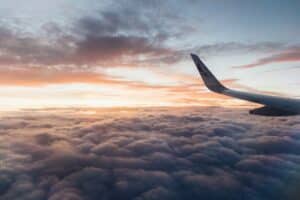airplane wing and sunset over clouds in flight