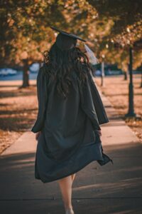 female student in cap and gown walking away